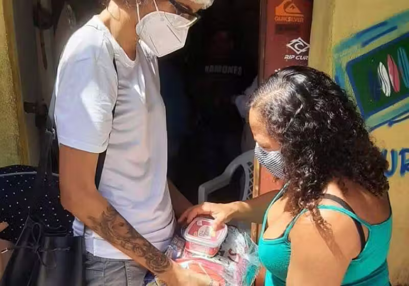 Na última ação promovida pelo Onda Solidária, na Barra do Ceará, a advogada e surfista Tayane Sales (à esq., de branco) entregou cestas básicas. - Foto: arquivo pessoal