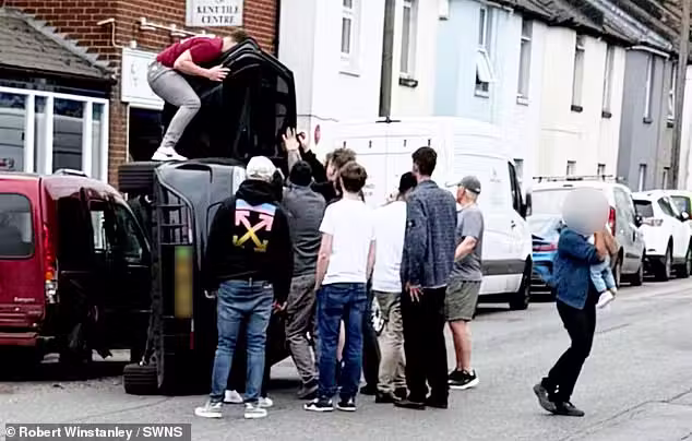 Os jovens salvando a família que capotou com o carro. Um deles sai cok o bebê no colo (dir). - Foto: SWNS
