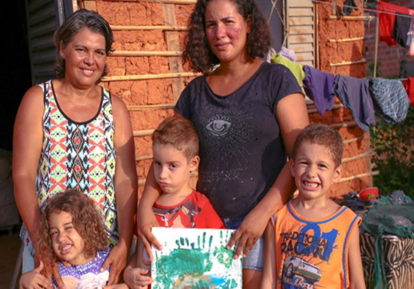 Isaac com o desenho e a família na casa de taipa Foto: reprodução Cidade Verde 