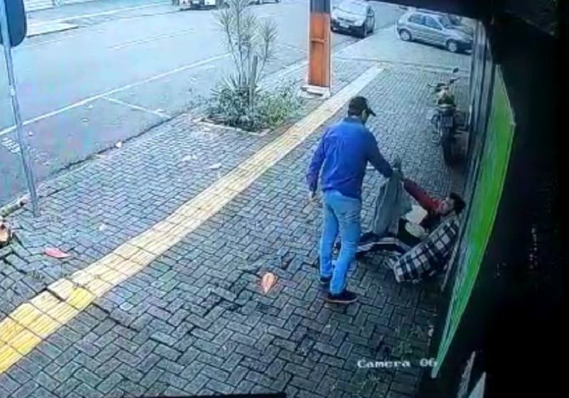 O vendedor ambulante Gabriel doando a própria blusa à pessoa em situação de rua - Foto: câmeras de segurança / G1