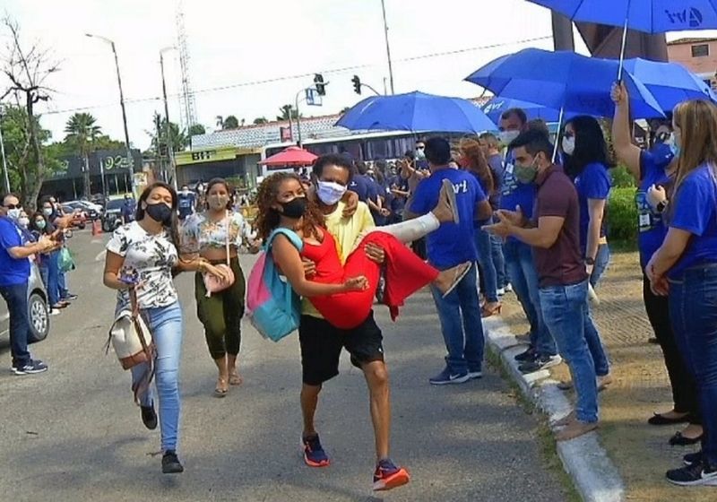 O professor carregando a aluna com a perna enfaixada, que ia perder o vestibular - Foto: O Povo