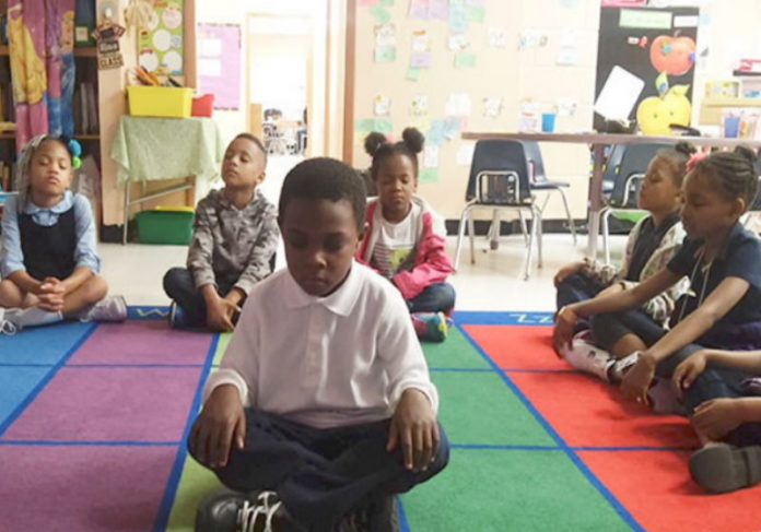 Crianças meditam durante aula como forma de alcançar o equilíbrio e bem-estar Foto: Holistic Life Foundation