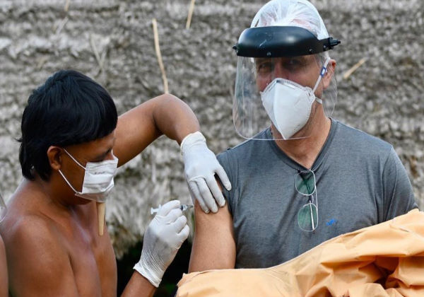 dr. Erik sendo vacinado por um indígena da tribo Foto: Márcia Moreira/Divulgação