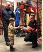 Oliver conhecendo as dependências e o uniforme dos bombeiros - Foto: Divulgação / Corpo de Bombeiros de Parksville