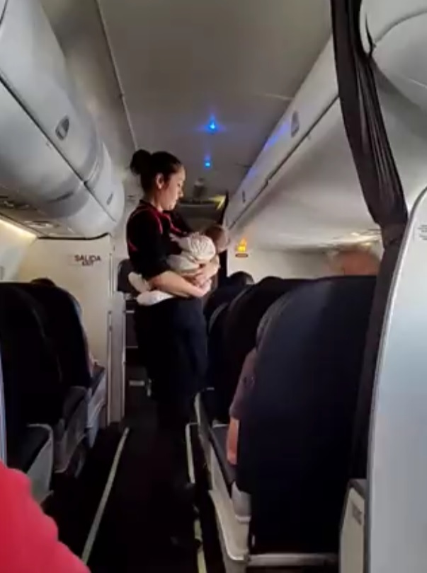 A aeromoça caminha com o bebê no colo durante o voo. Gesto emocionou! Foto: Reprodução/@mapo_portillo/Twitter.