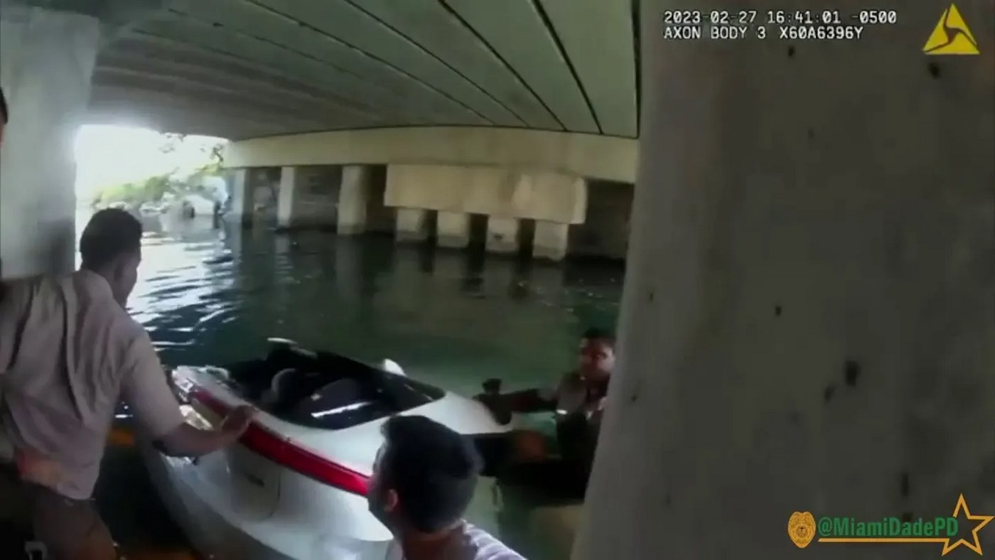 Uma câmera acoplada em um dos policiais filmou toda a ação da equipe de resgate para salvar a criança que estava presa na cadeirinha do carro submerso. Foto: Reprodução/Local 10.