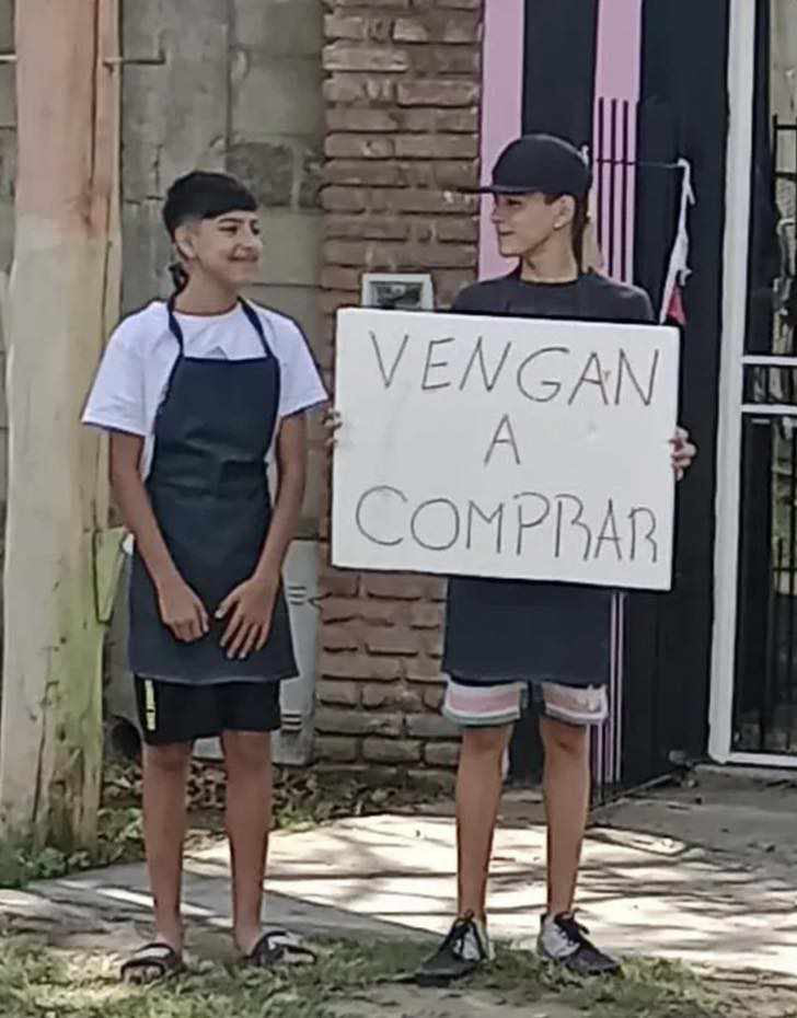 O garoto segurando o cartaz para chamar clientes para o comércio de bolos da mãe. A ideia singela deu certo. - Foto: reprodução / Luján 365