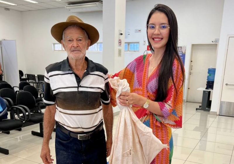 A gerente segurando a galinha viva que ganhou de presente do cliente idoso, grato pelo bom atendimento - Foto: reprodução / Linkedin @carolinetimoteo