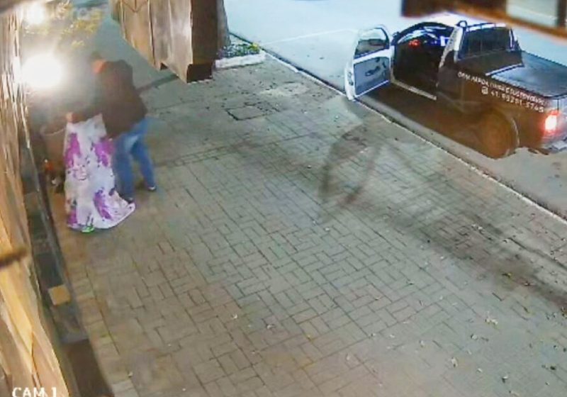 Câmeras de segurança de uma loja flagraram o momento em que o motorista para o carro e leva um cobertor para aquecer um homem em situação de rua em Araucária, PR - Foto: reprodução / Facebook