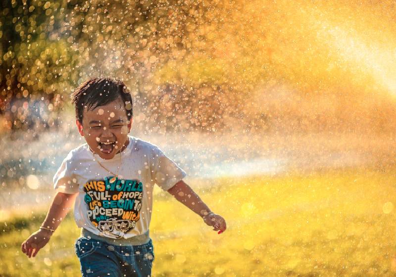 A alegria de tomar um banho de chuva, ou de mangueira. Crianças ensinam com atos simples como ser feliz, ou ter momentos de felicidade. - Foto: phammi / Unsplash