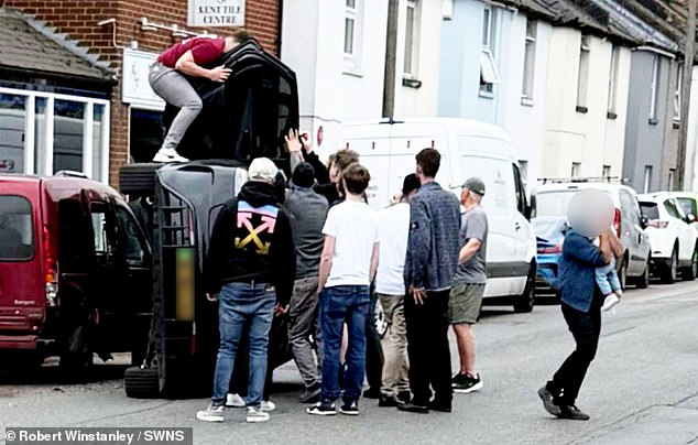 Os jovens salvando a família que capotou com o carro. Um deles sai cok o bebê no colo (dir). - Foto: SWNS
