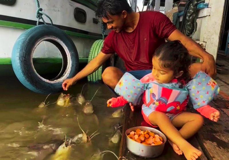 Enak, conhecido como o "encantador de peixes", é um pai que ensina a filha a alimentar os animais no rio Solimões no Amazonas. Foto: reprodução/ Instagram / @enak.carvalho