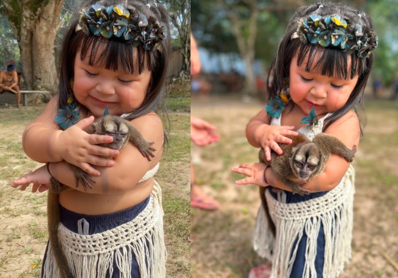 A Safira Louise, de 1 ano, segura um macaquinho durante celebração tradicional do povo Parintintin, no Amazonas - Foto: Reprodução/Instagram/@joparintintin