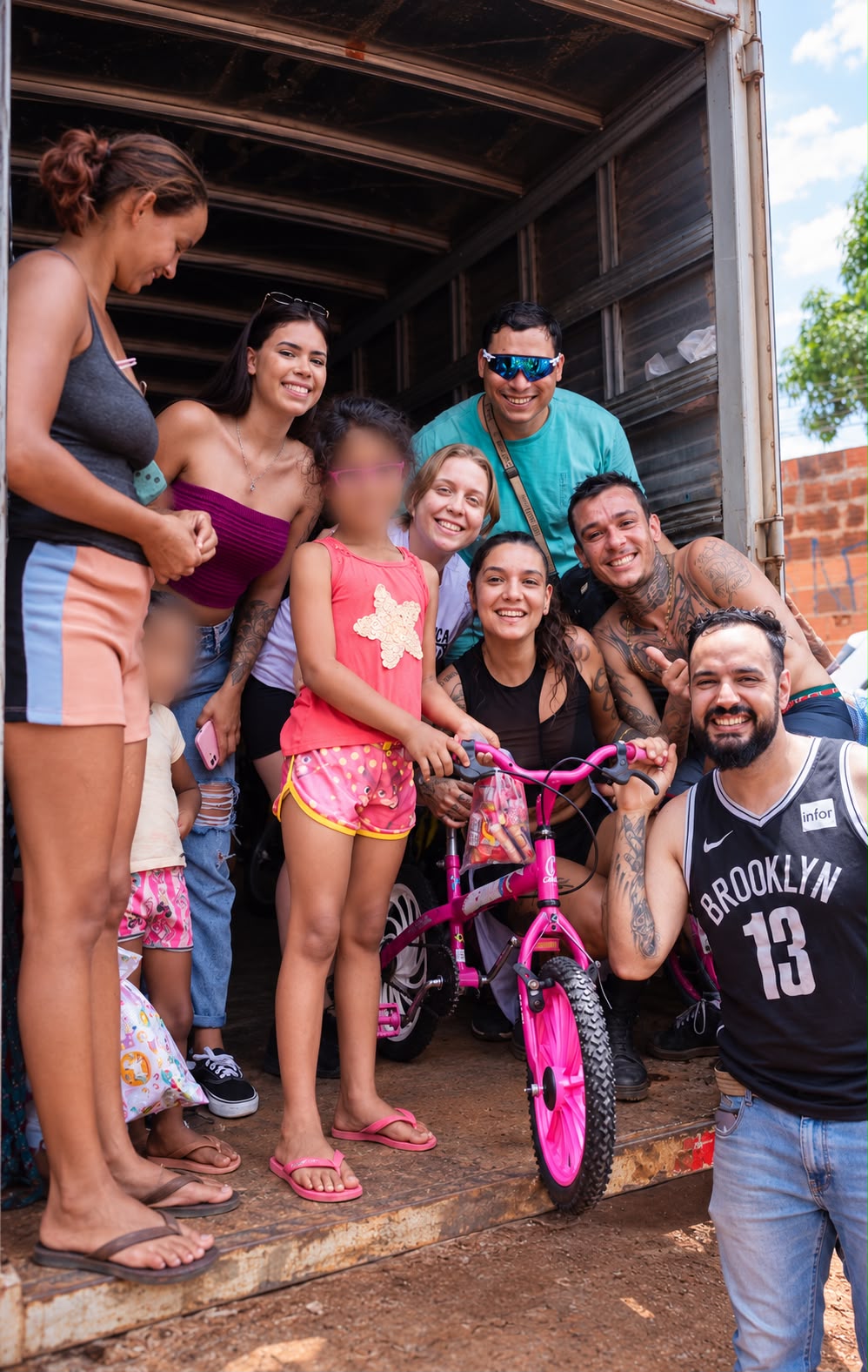 Equipe entrega uma bicicleta a uma criança durante a distribuição de doações. Foto: Arquivo pessoal/Reprodução/Instagram/@diadascriancasnaquebrada