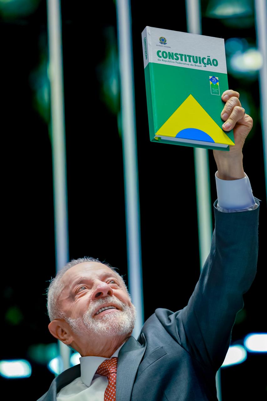 O presidente Lula levanta a Constituição brasileira onde agora estará registrado o fim da escala 6x1. - Foto: Ricardo Scuckert/ PR